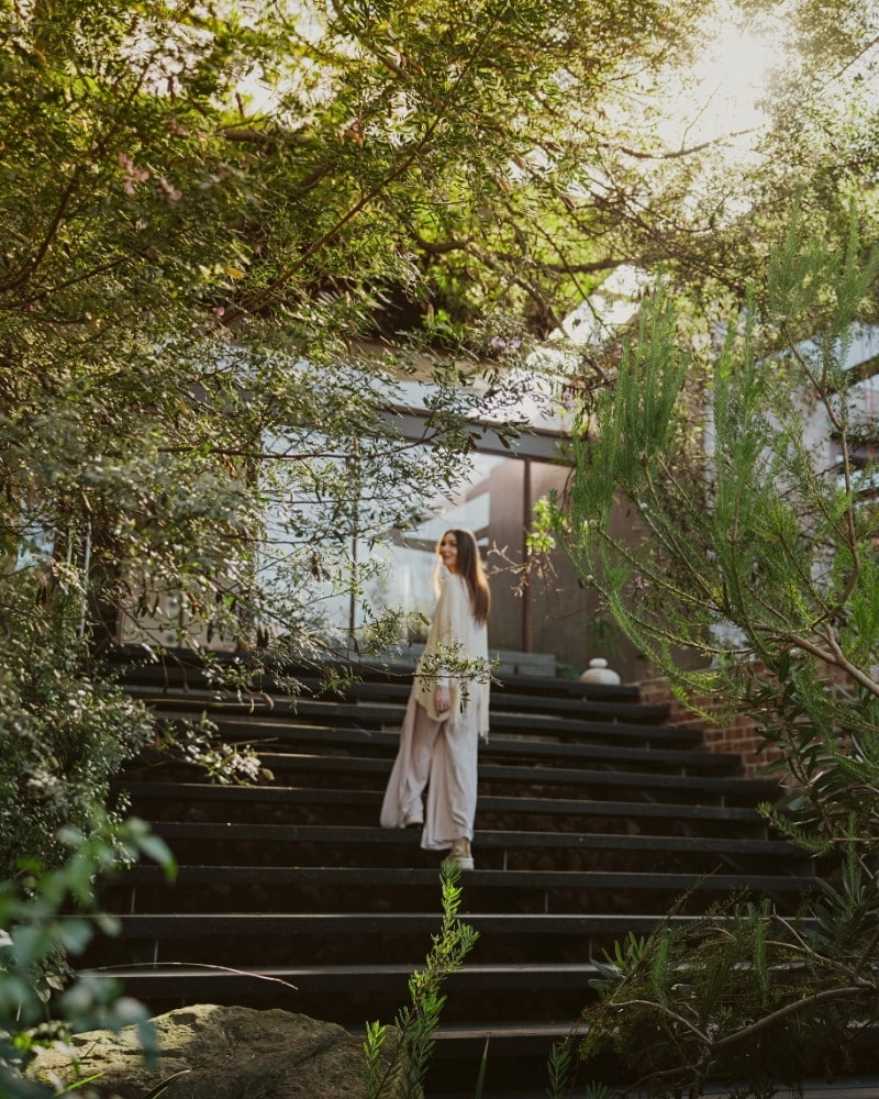 Woman walking up stone steps towards the main entrance of Phakalane Retreat in Hout Bay, South Africa.