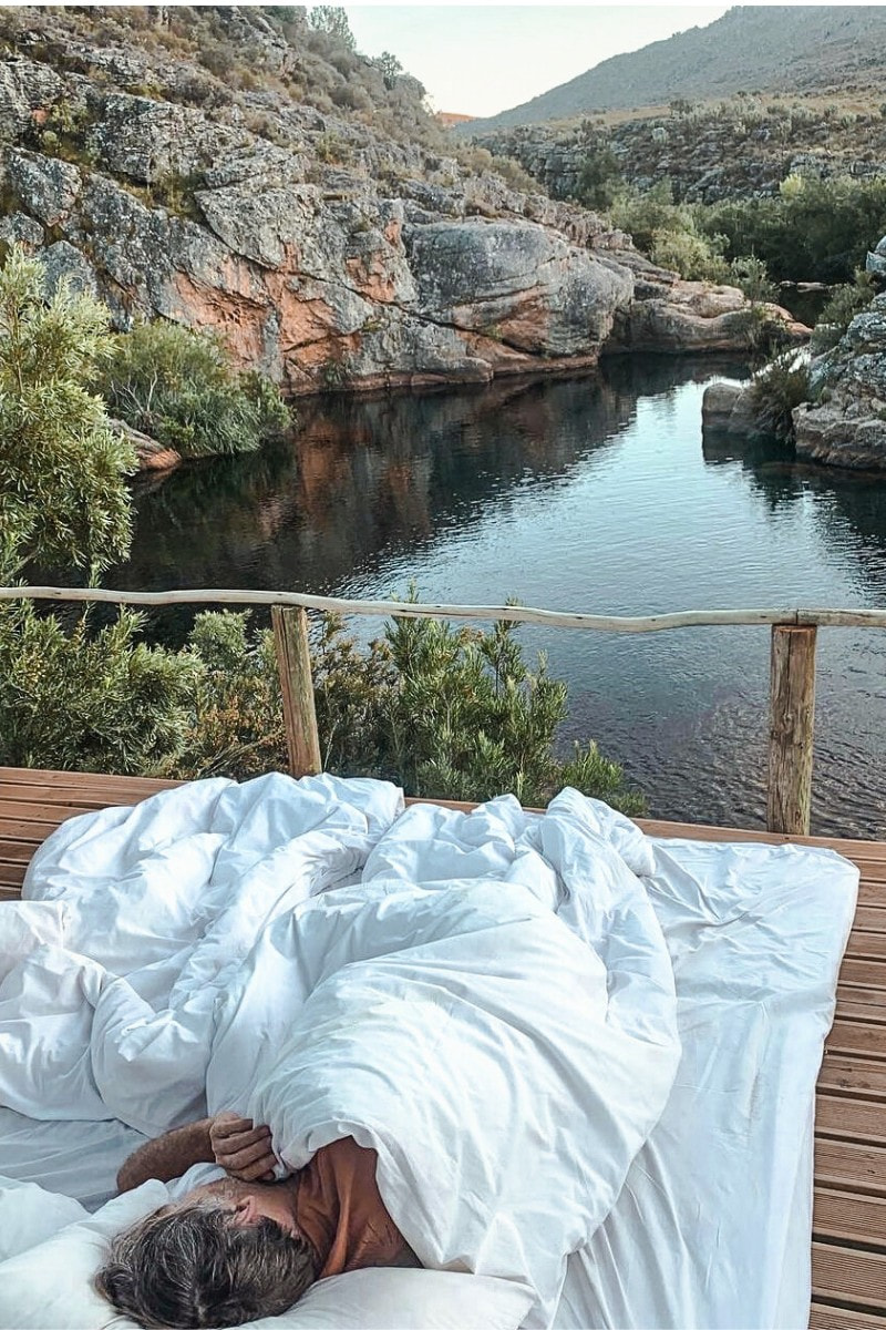A man sleeps on an outside deck overlooking the river