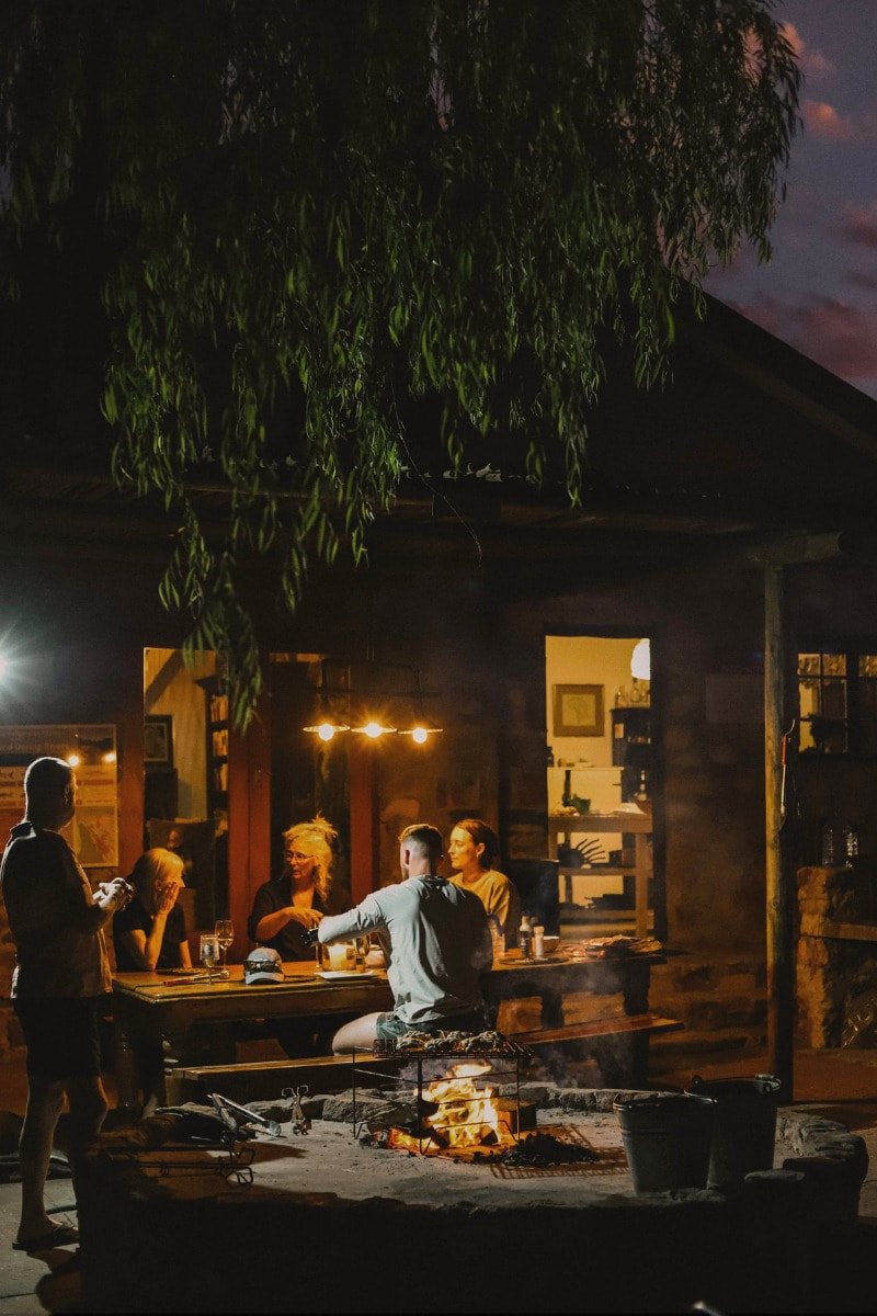 A family gathers around a fire in the evening at a holiday cottage
