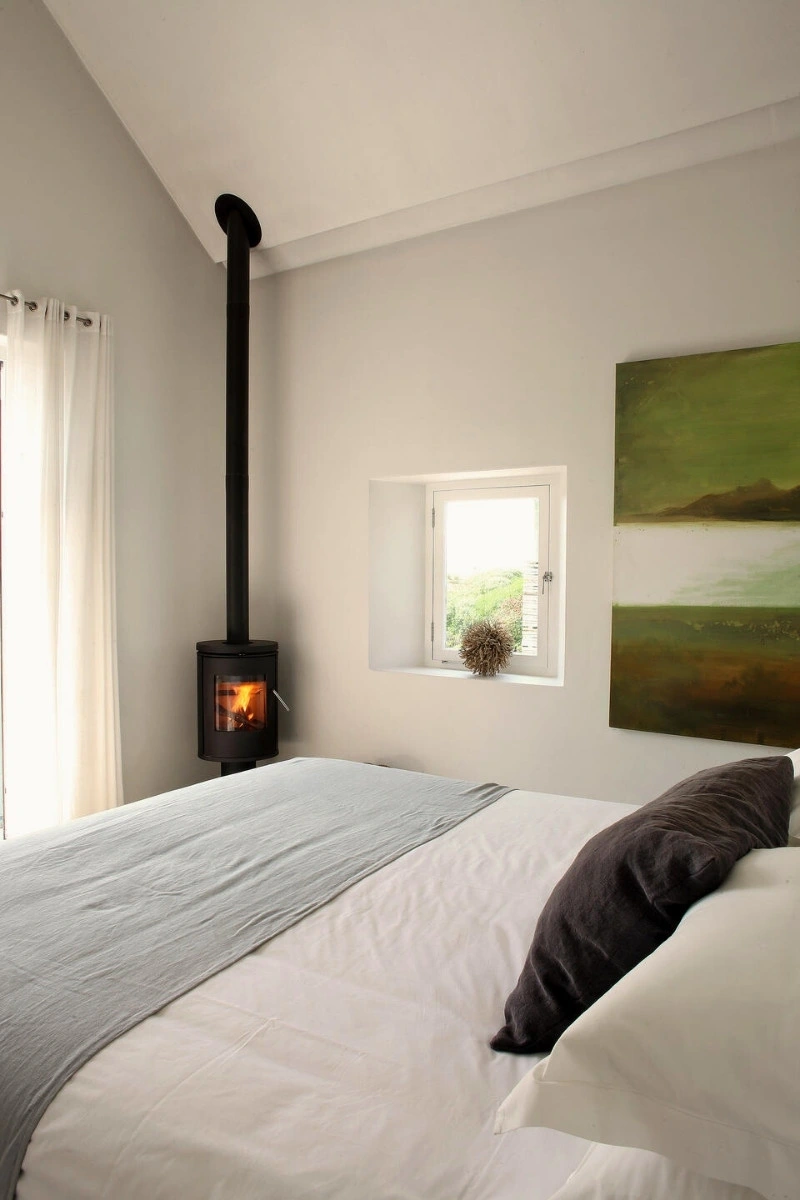 Luxury bedroom with fireplace and original artwork at Strandloper Ocean Boutique Hotel, Paternoster, West Coast South Africa