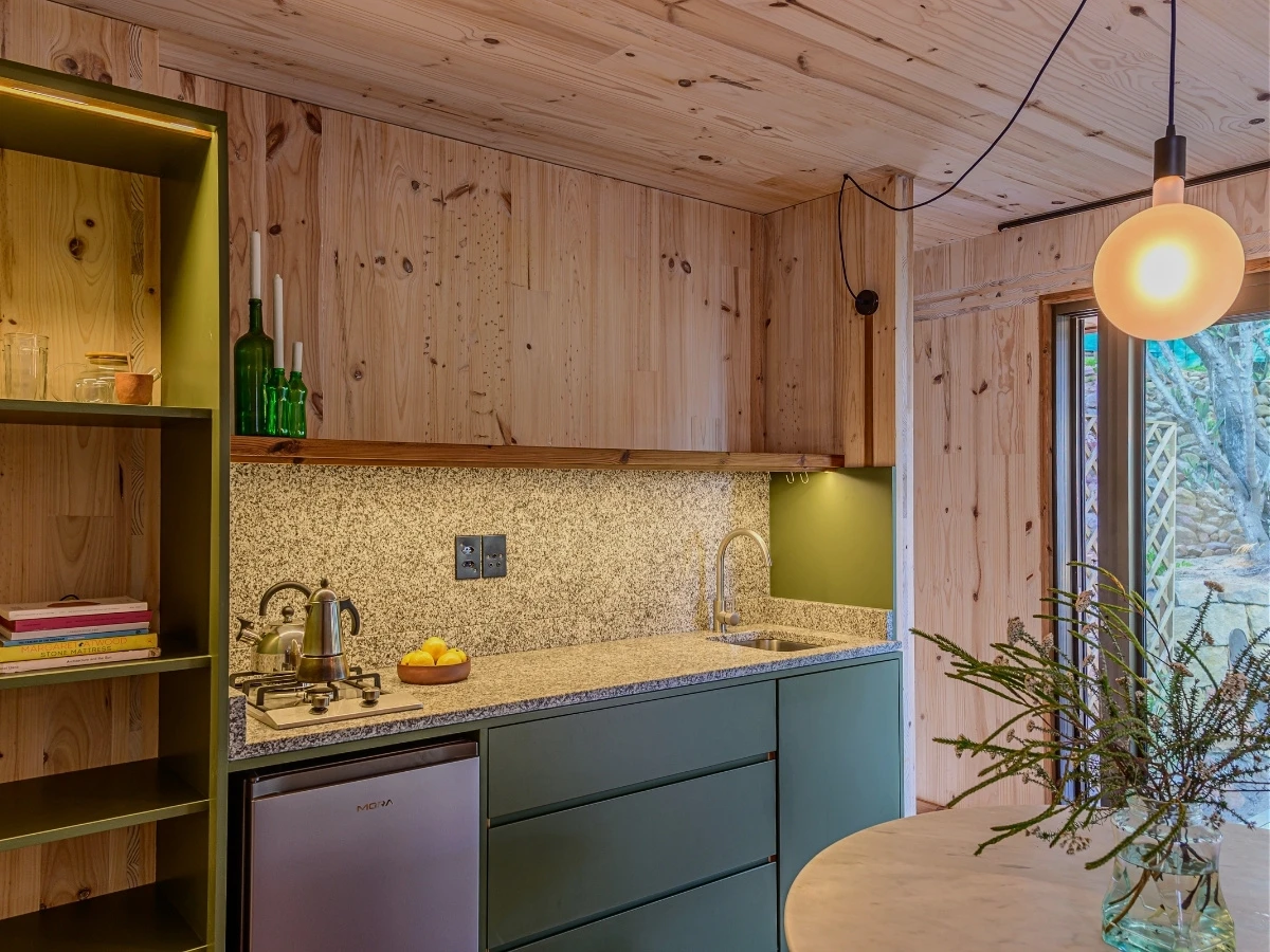 Mini-kitchen tucked into a single wall of joinery at Licorne Studio in Muizenberg — gas hob at one end, sink at the other, marble counter with a single shelf above and sliding drawers below.