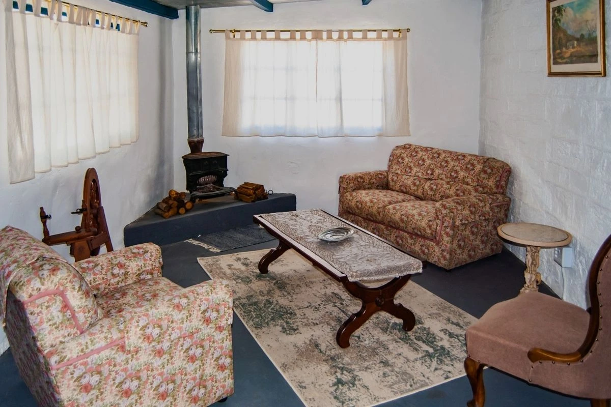 Cottage lounge with fireplace, blue painted floor and floral armchairs at Nigramoep farm stay, Namaqualand