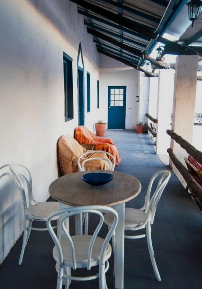 Blue stoep with couches and a wooden table at Nigramoep, shaded outdoor seating for guests in Namaqualand