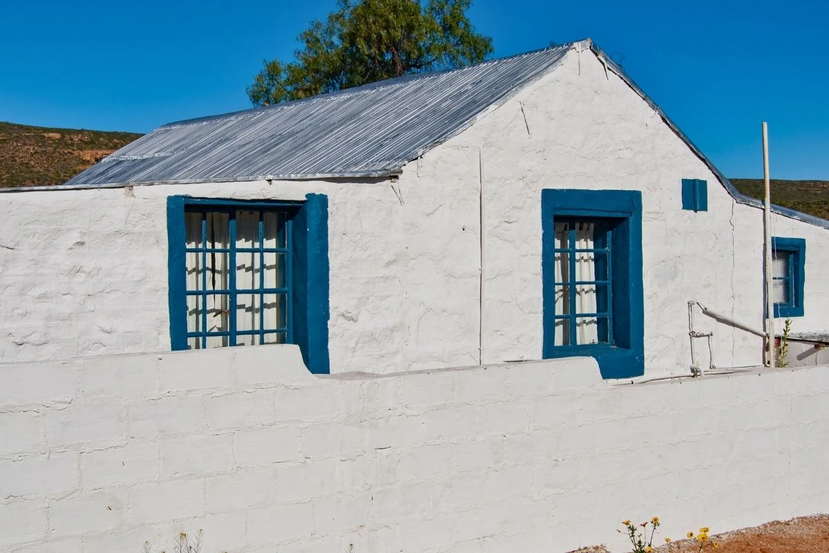 Whitewashed self-catering cottage with blue window frames at Nigramoep Slowliving Guest Farm near Springbok