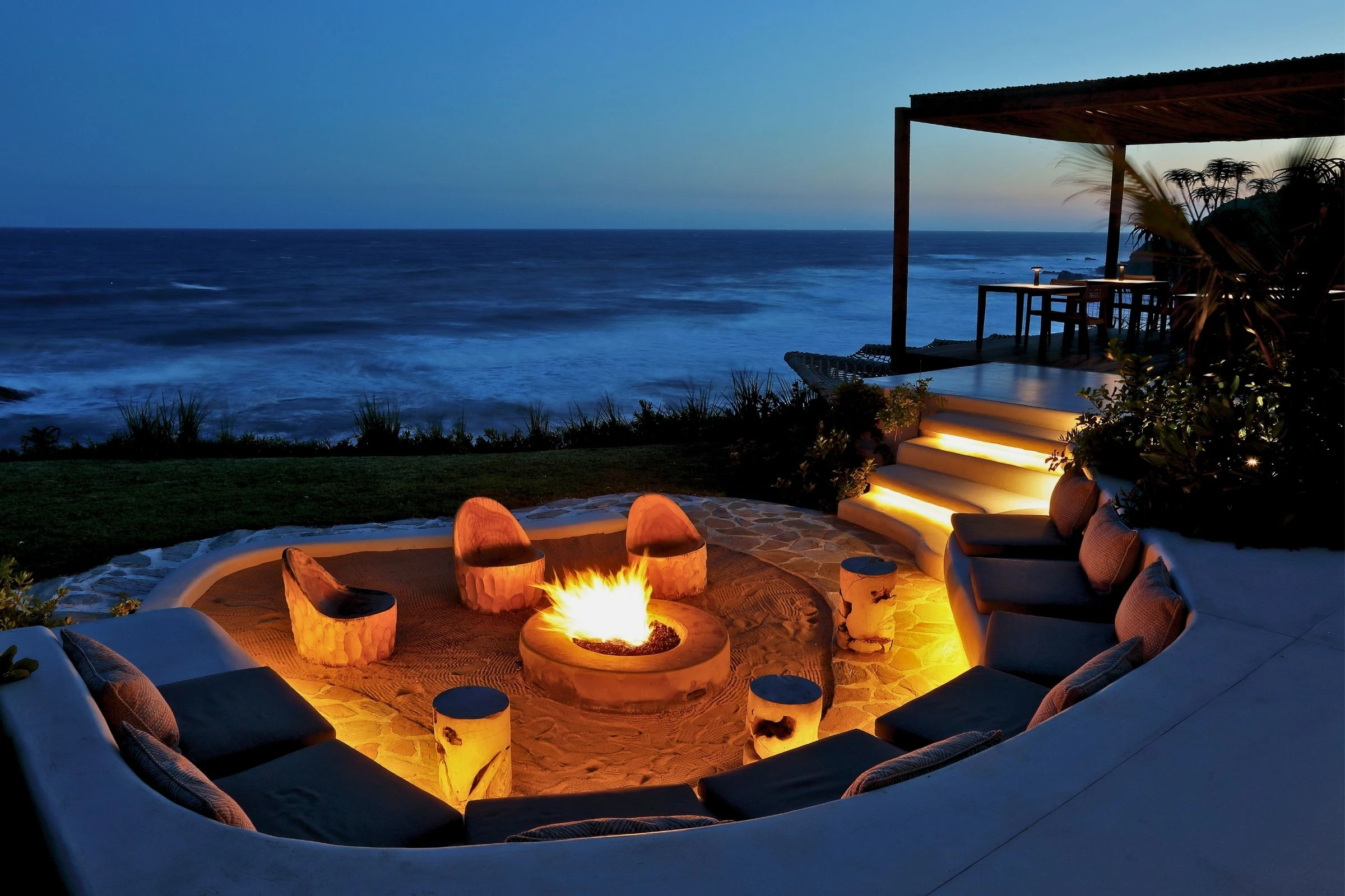 Firepit with cushioned bench lit at night above the Indian Ocean, Sala Beach House, Ballito