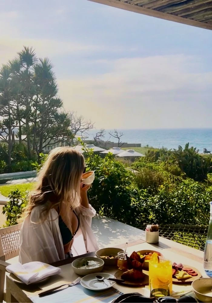 A guest having breakfast on the dining deck at Sala Beach House, overlooking the ocean