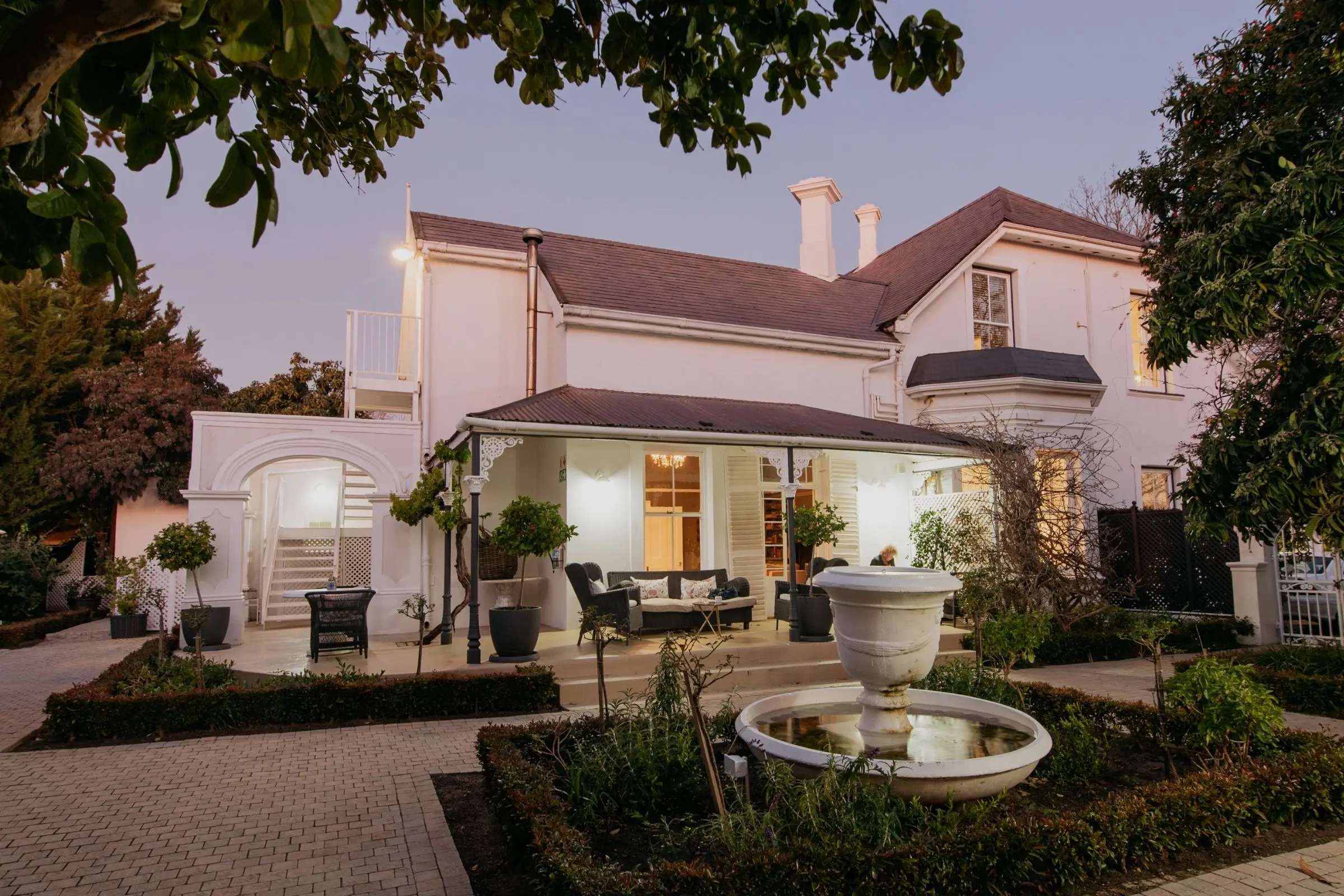 River Manor Boutique Hotel's heritage facade at dusk with fountain in the foreground, Stellenbosch