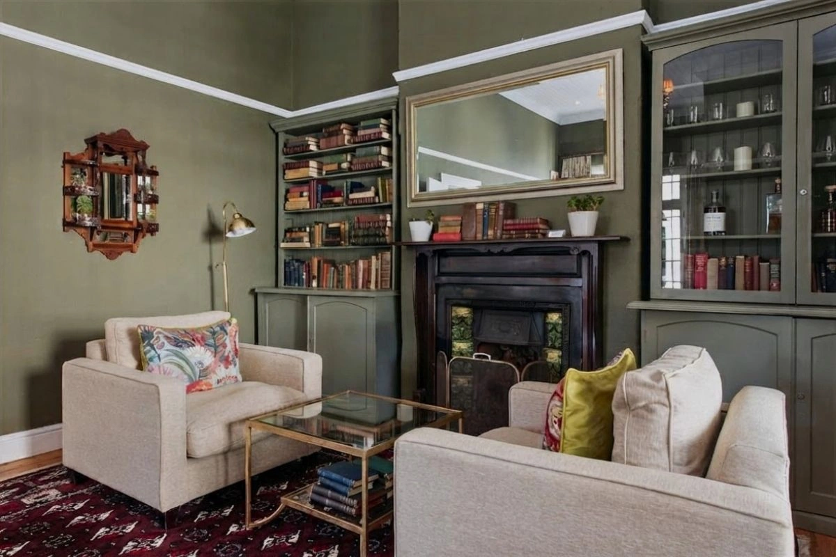 Fireplace lounge with bookshelves and armchairs inside River Manor Boutique Hotel's heritage building