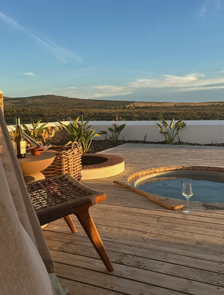 Deck chair and a glass of wine beside the wood-fired hot tub on a Veldt Haus deck at De Wildeveldt