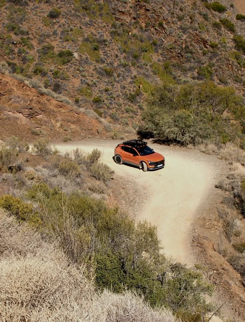 Aerial view of the winding gravel road into Gamkaskloof, with a small orange car on one of the bends.