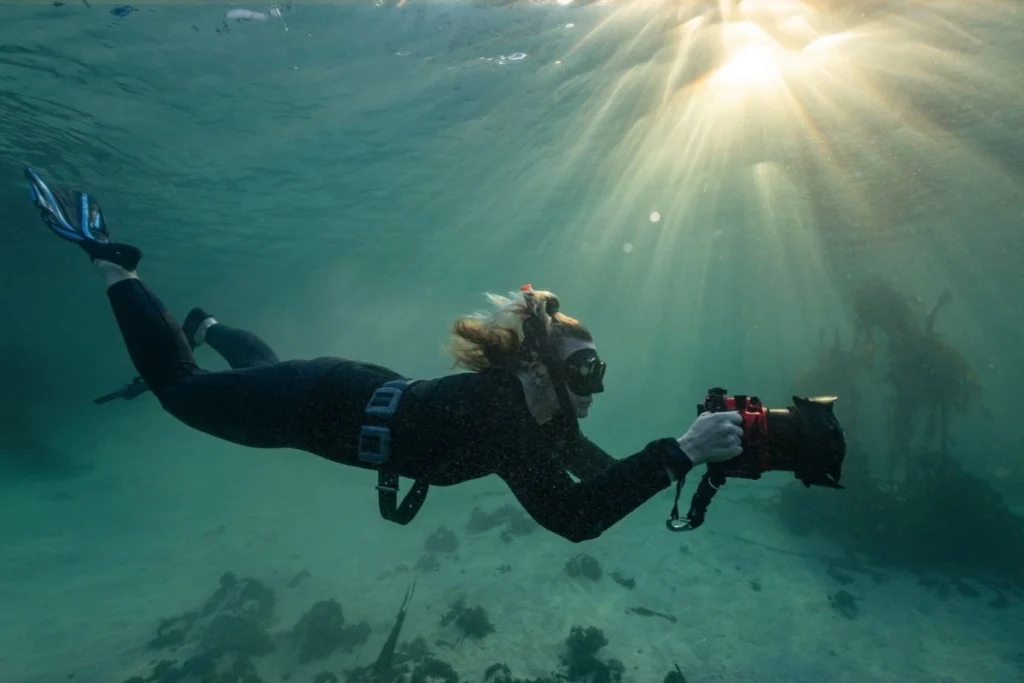 Underwater photographer Helen Walne in a wetsuit with her camera in the water in False Bay